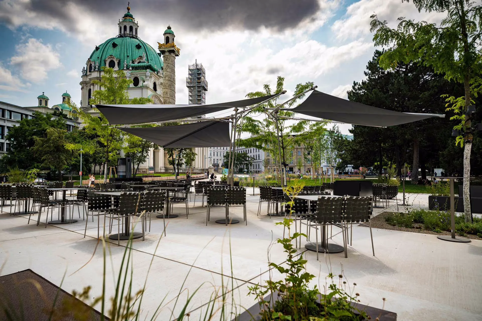 Anthrazitfarbene Sonnensegel über einer Außengastronomie mit Blick auf eine Kuppel